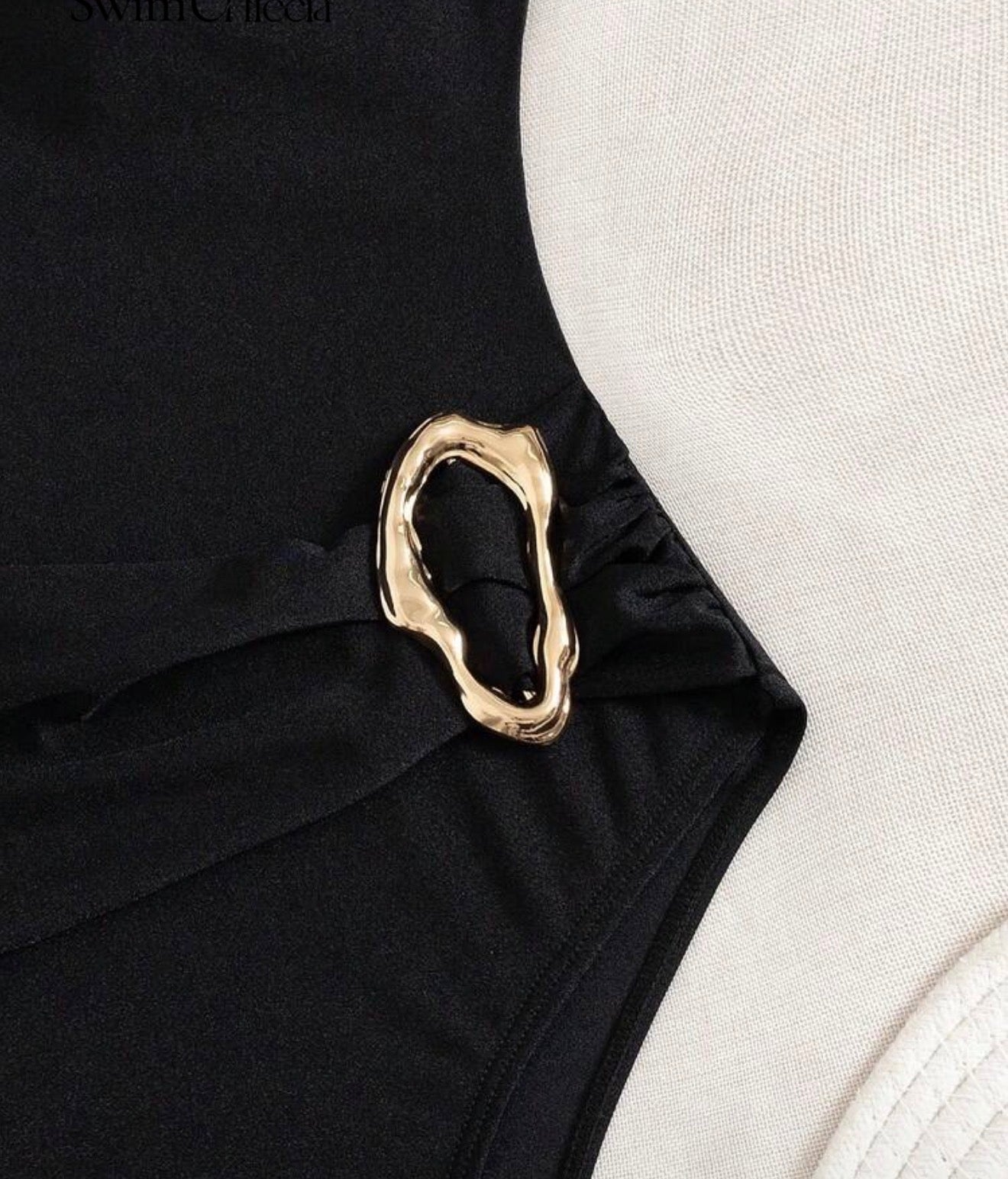 Detalle de joyería metálica dorada en la cintura del traje de baño