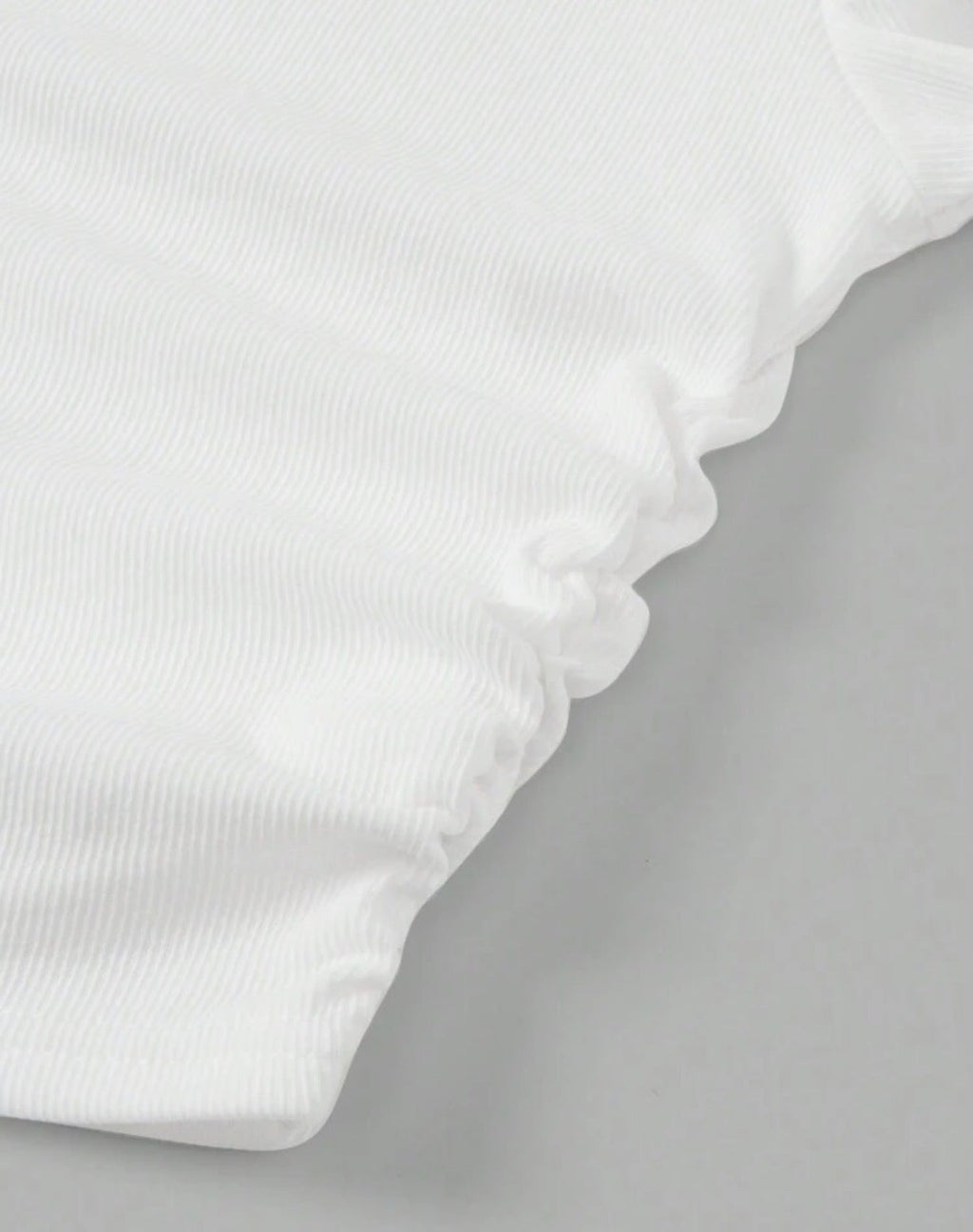 Detalle dobladillo ondulado del top blanco