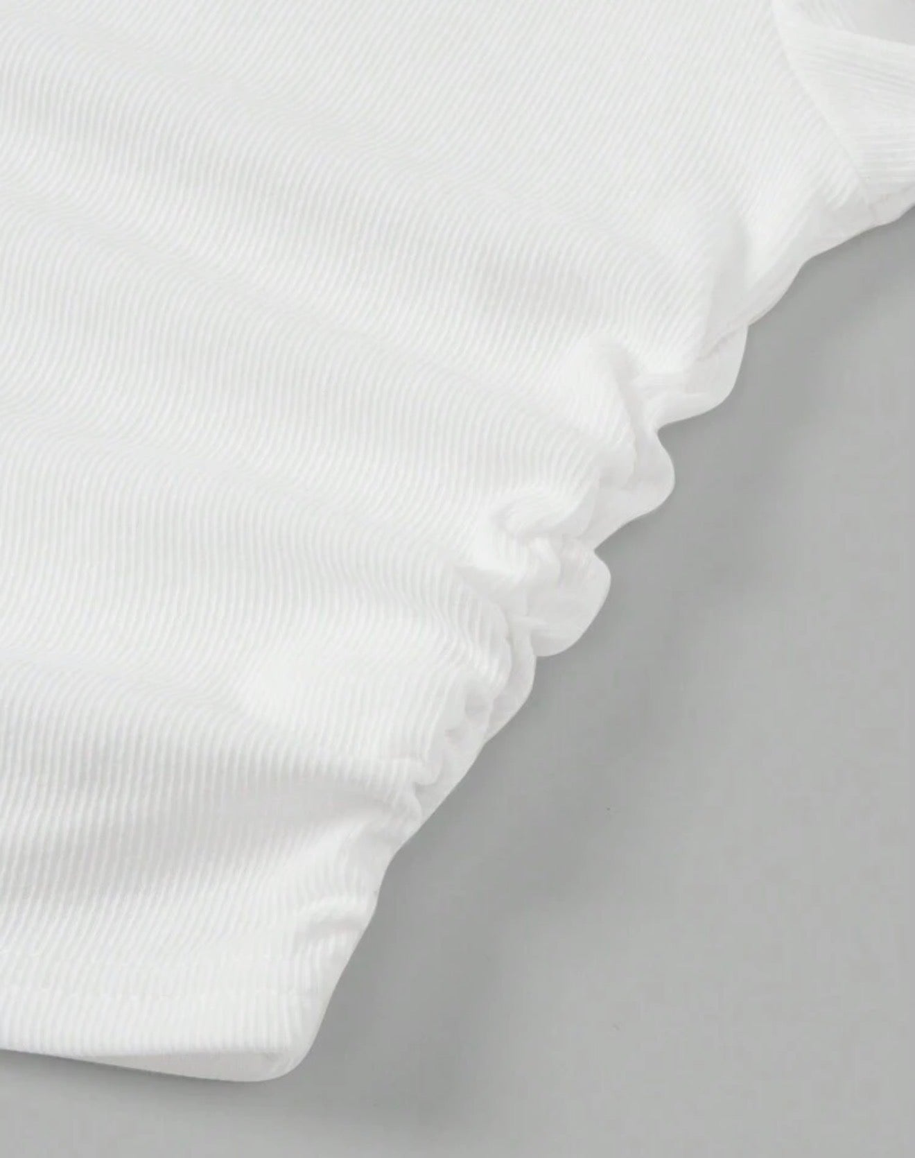 Detalle dobladillo ondulado del top blanco